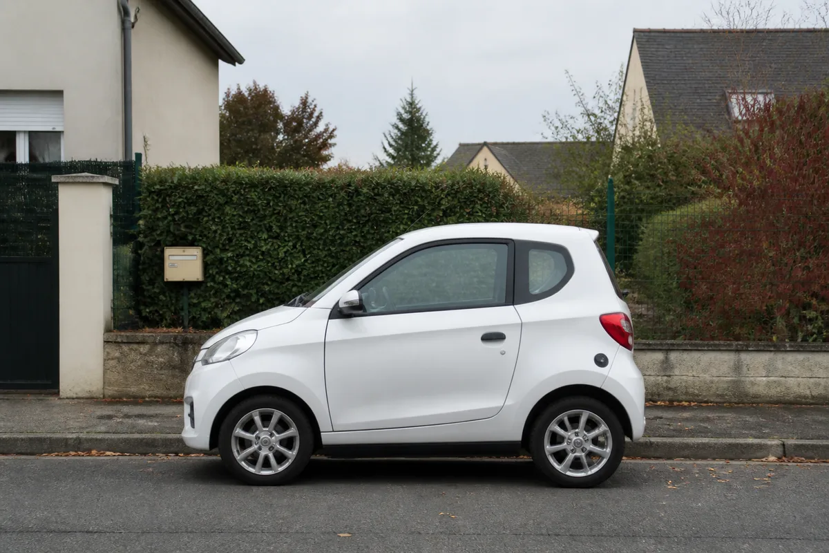 Petite voiture sans permis blanche stationnee le long d une rue pavillonnaire